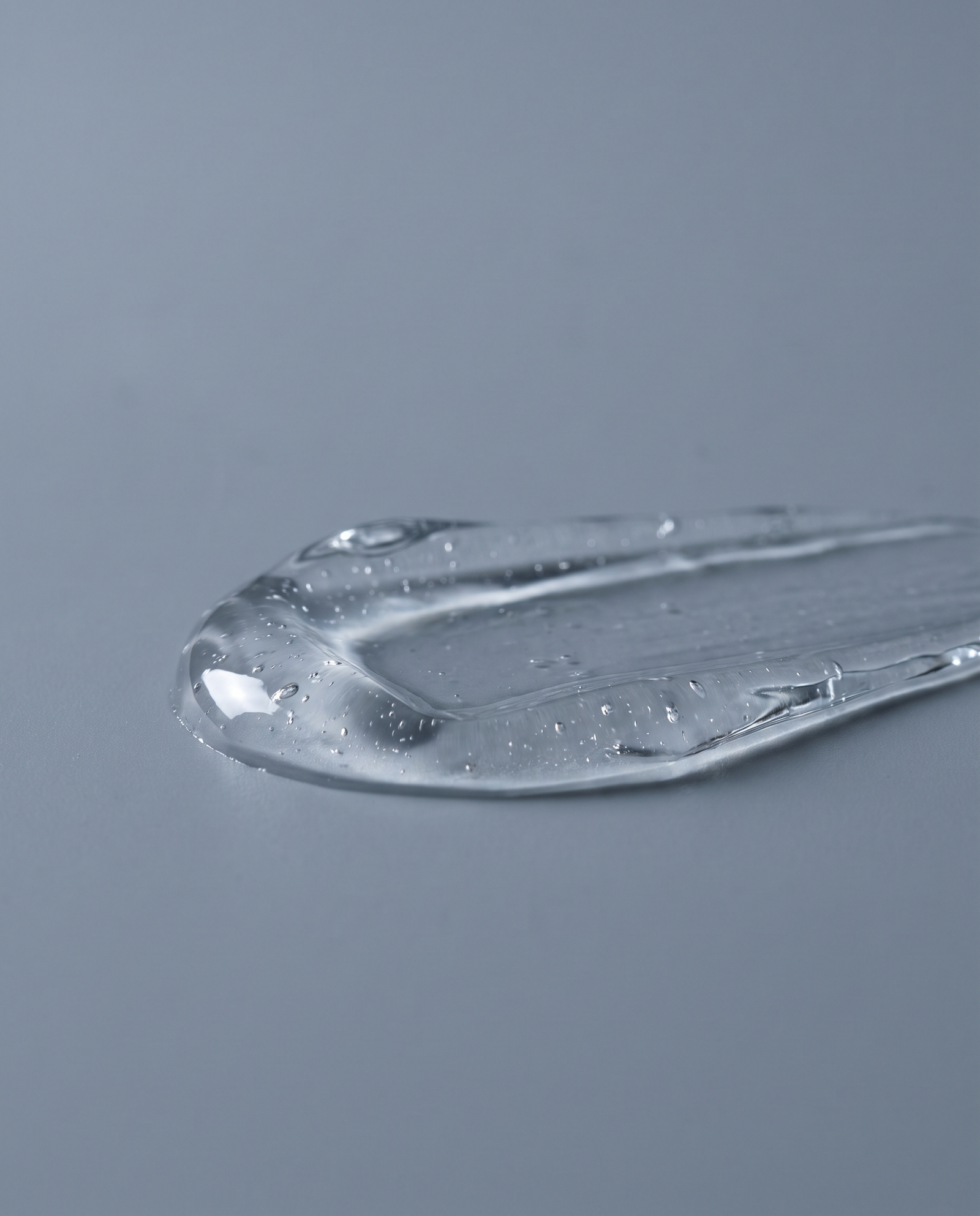 Macro of clear serum texture on a pale grey backdrop
