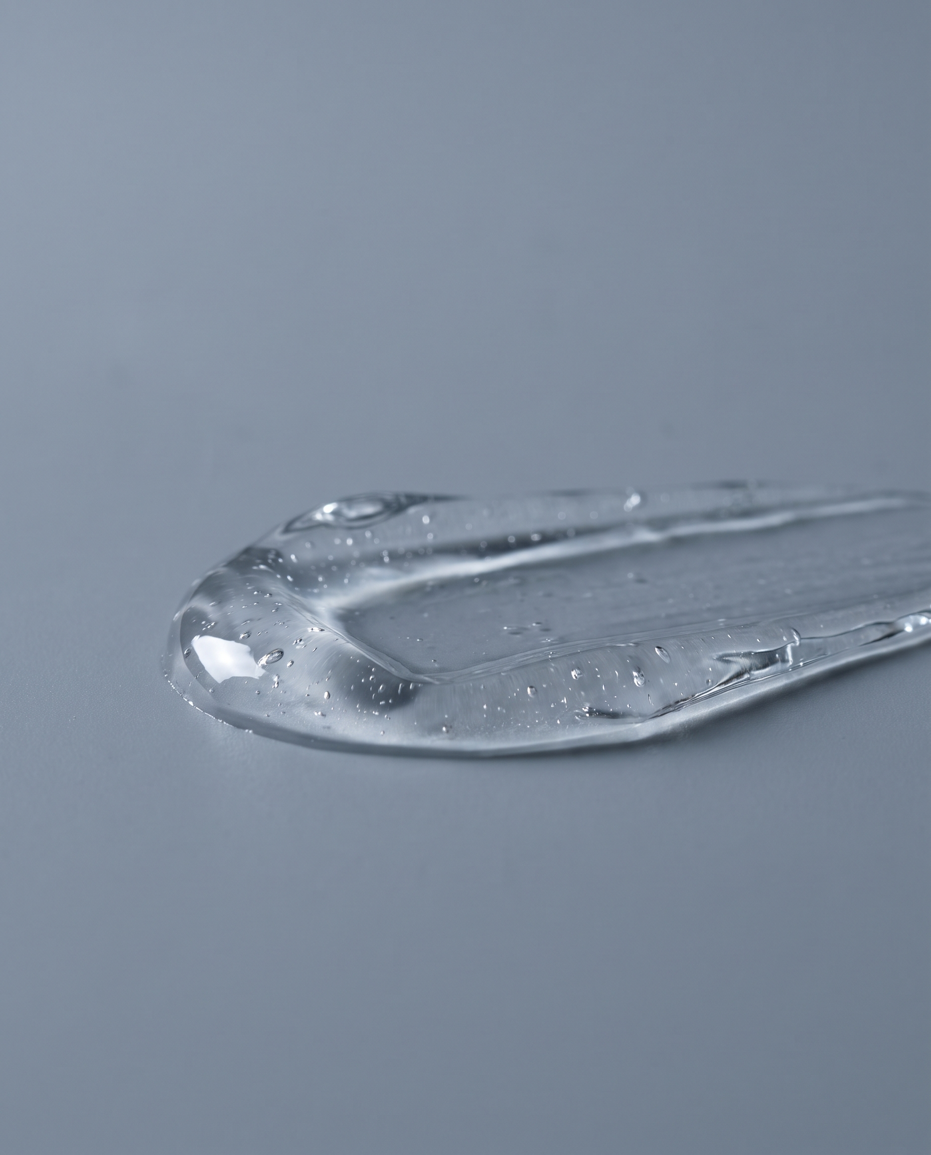 Macro of clear serum texture on a pale grey backdrop